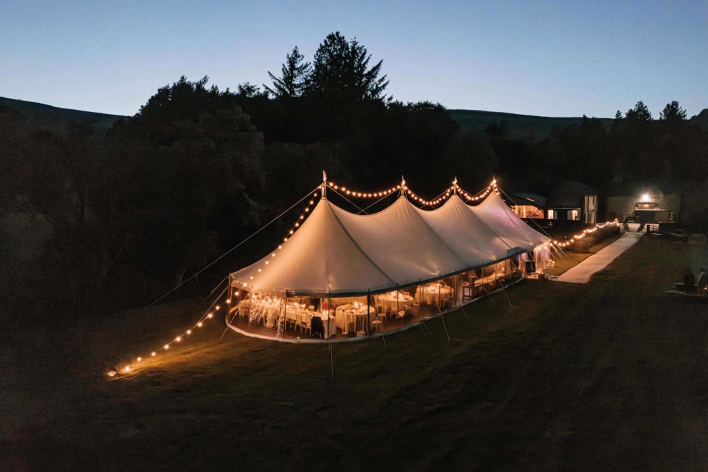 Elegant sailcloth marquee set up in a scenic Peak District meadow surrounded by rolling hills.